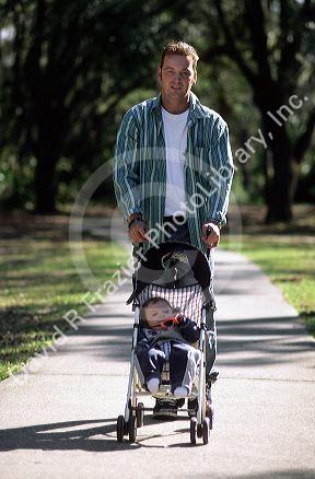 Father pushing his infant son in a stroller.