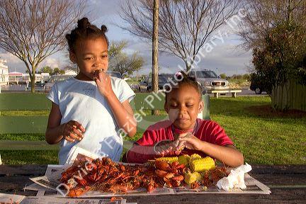 African american girls eating crawfish and corn on the cob in New Orleans, Louisiana.