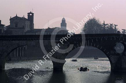 Boats float under the bridge in Verona, Italy.