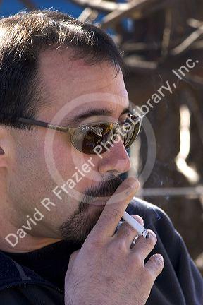 A middle aged man smoking a cigarette.