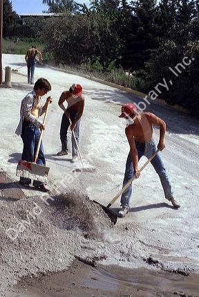 People wearing face masks clean up ash in the aftermath of the Mount St. Helens eruption 1980. Pullman, Washington.