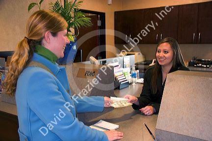 Customer depositing cash at a teller window.