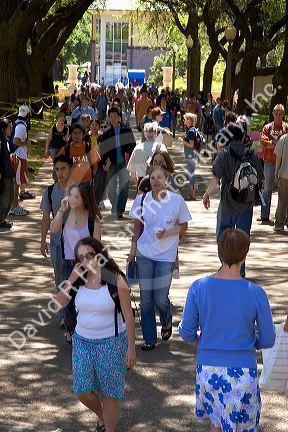 Students walking and using cell phones on the campus of University of Texas in Austin.