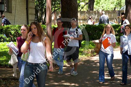Students walking and using cell phones on the campus of University of Texas in Austin.