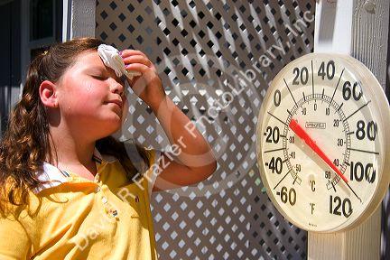 Nine year old girl wipes sweat from her forehead in 100 degree weather.
