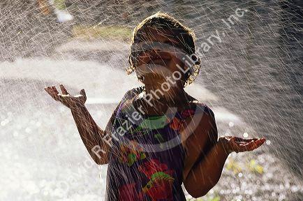 Six year old girl playing in a lawn sprinkler.
