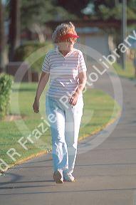 Senior citizen walking on a path through a park.