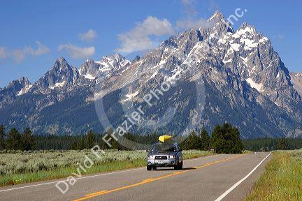 Vehicle traveling with canoe on roof on the highway through Grand Teton National Park, Wyoming.