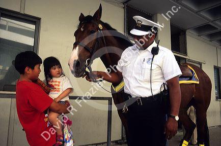 An african american police officer with horse talks to asian children in Cincinnati, Ohio.