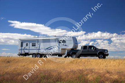 A truck pulling a camper trailer on the highway.
