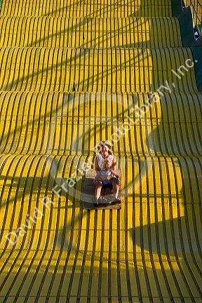 Mother and daughter ride down a giant yellow slide at the Iowa state fair in Des Moines.