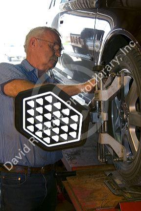 Technician performing wheel alignment on automobile.