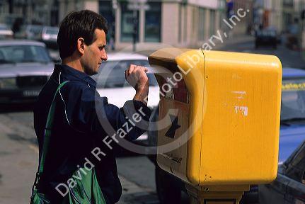 French man deposits a letter into a mailbox in France.