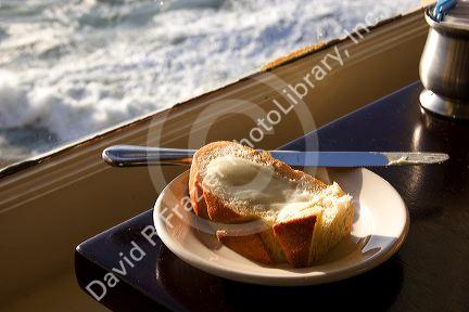 A piece of buttered bread and ocean view at The Cliff House Restaurant on the San Francisco Coast, California.