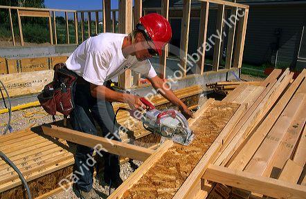 Construction worker using a power saw to cut an I-beam to size.
