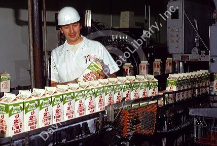 An employee inspects cartons of milk on a conveyer line at a dairy processing plant in Boise, Idaho.