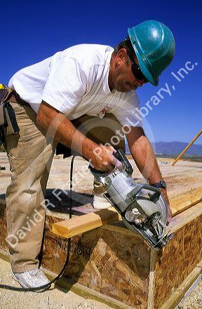 Carpenter concentrates while cutting lumber with a power saw.