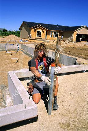 Housing construction worker uses a level to install a pipe in Boise, Idaho.
