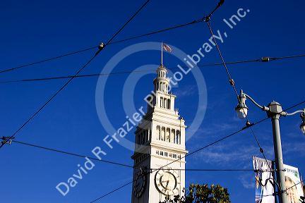 Clock tower on the Ferry Building in San Francisco, California seen through the wires powering trolley cars.