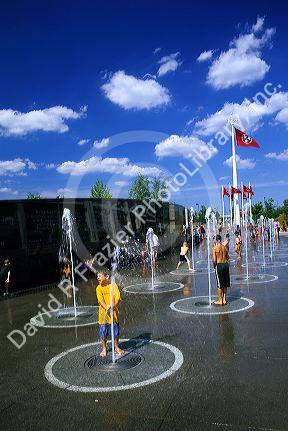 Children play in water fountains in front of the Tennessee River story wall at the Capitol Mall in Nashville, Tennessee.
