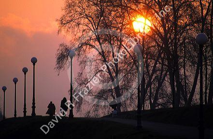 People walk along a path at sunset in Lucca, Italy.