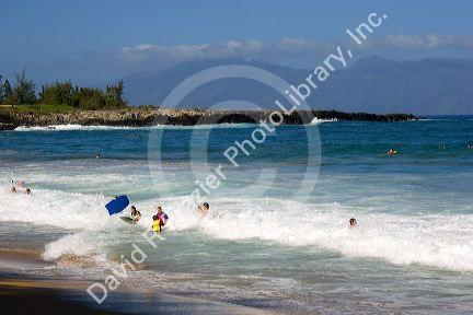 Boogie boarding on waves in the pacific ocean off the island of Maui, Hawaii.