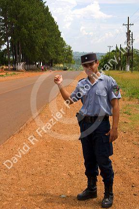 A police officer hitch hiking on the side of a road in Argentina.