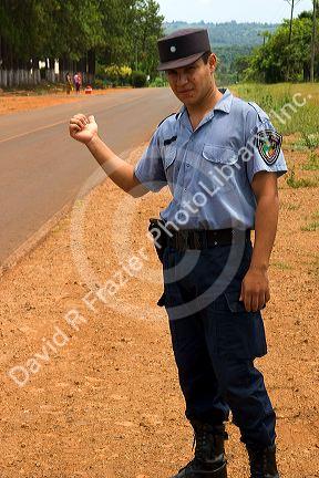 A police officer hitch hiking on the side of a road in Argentina.