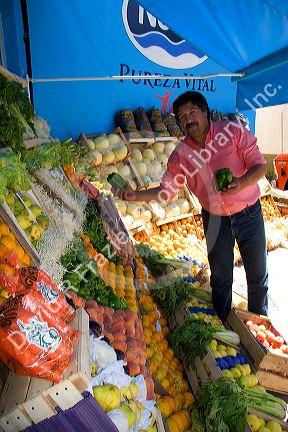 Merchant arranges artistic display of fruit and vegetables at a stand in Gesell, Argentina.