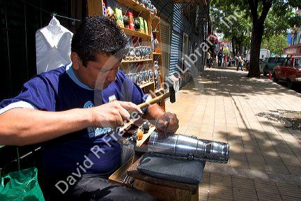 Vendor making and selling silver cups in the La Boca area of Buenos Aires, Argentina.
