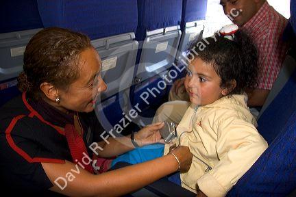 Flight attendant helping a child buckle her seatbelt on an airplane in Argentina.