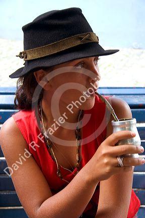 Argentine woman drinking yerba mate out of a silver cup with a straw in the La Boca area of Buenos Aires, Argentina. (model released)