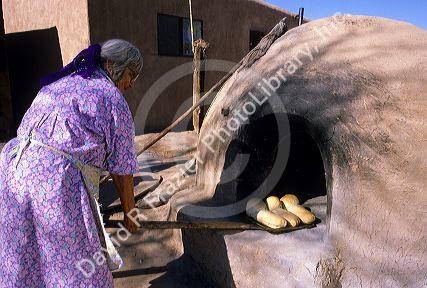 Indian pueblo woman uses an outdoor oven for baking bread in Taos, New Mexico.