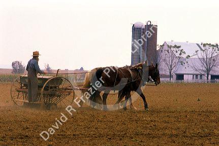 Amish farmer using a horse drawn seed planter in Lancaster County, Pennsylvania.