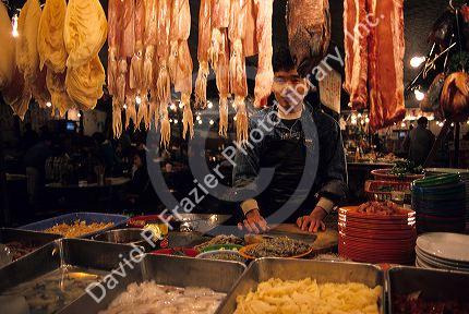 A man works at a night market selling meat and fish in Hong Kong.