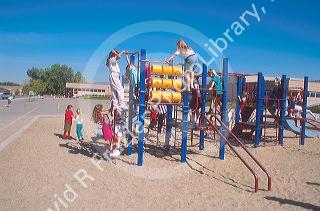 Elementary school students climbing on playground toys.