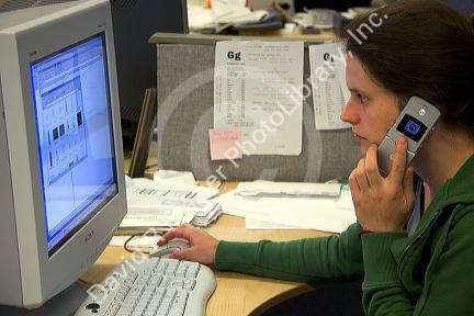 Office worker using a computer and cell phone. MR