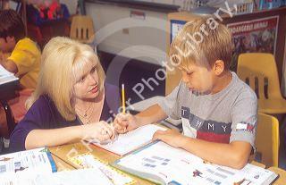 Elementary school teacher helping child with his school lesson.