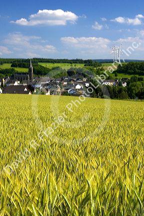 Electricity wind generators near a village in northwest Germany with a barley field in the foreground.