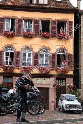 A man wearing motorcycle riding gear and talking on a cell phone in front of apartments in the village of Ribeauville, Eastern France.