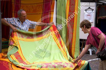 A woman purchasing a table cloth at an open air market in the village of Ribeauville, Eastern France.