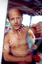 Brazillian fisherman holding a piranha on a riverboat on the Amazon River in Manaus Brazil.