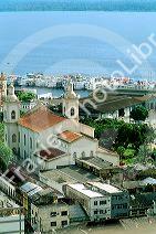 Scenic overview of Manaus Brazil showing buildings, Amazon River and riverboats docked.