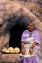 Indian pueblo woman uses an outdoor oven for baking bread in Taos, New Mexico.