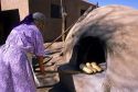 Indian pueblo woman uses an outdoor oven for baking bread in Taos, New Mexico.