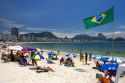 Visitors at the Copacabana Beach in Rio de Janeiro, Brazil and the flag of Brazil.