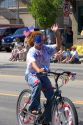 A girl with her face painted patriotic colors riding a bicycle in a small town Fourth of July parade in Cascade, Idaho.