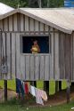 Brazilian girl in the window of her home in the Amazon jungle near Manaus, Brazil.