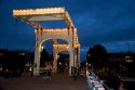 The famous Skinny Magere Bridge covered in lights at dusk over the Amstel River in Amsterdam, Netherlands.