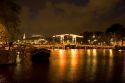 A drawbridge lit up at night on the Amstel River in Amsterdam, Netherlands.